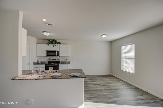 kitchen with dark stone counters, sink, light hardwood / wood-style flooring, appliances with stainless steel finishes, and white cabinetry