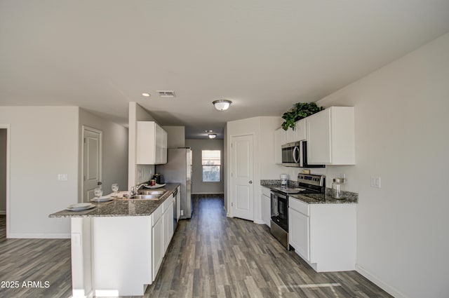 kitchen with white cabinets, dark hardwood / wood-style flooring, stainless steel appliances, and dark stone countertops