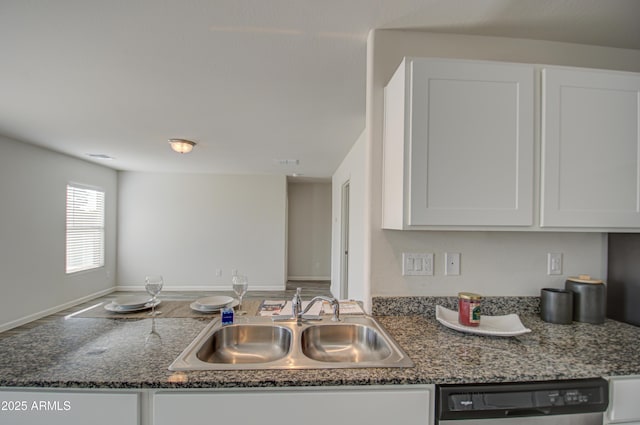 kitchen with white cabinets, stainless steel dishwasher, dark stone counters, and sink