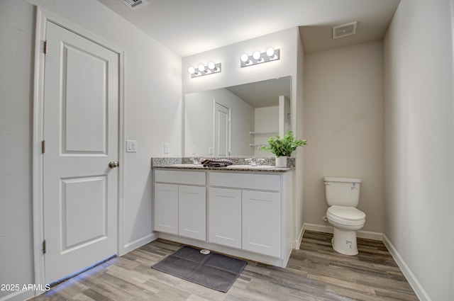 bathroom featuring vanity, hardwood / wood-style flooring, and toilet