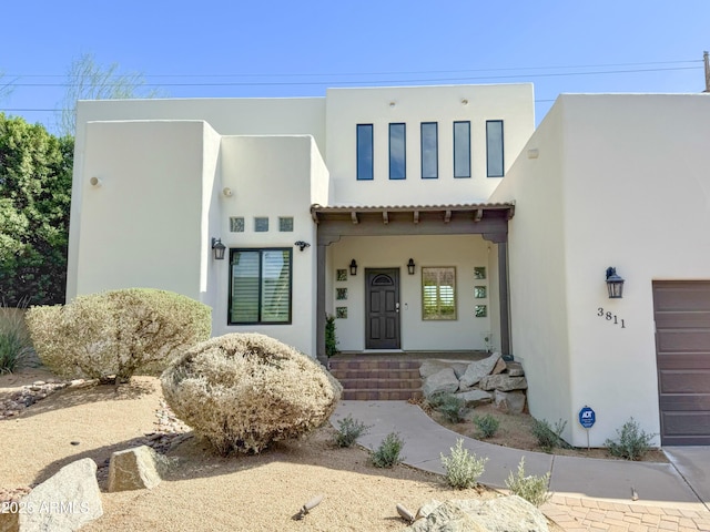 view of front of home with a tiled roof, stucco siding, an attached garage, and a porch