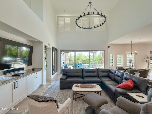 living area with visible vents, light wood-type flooring, and an inviting chandelier