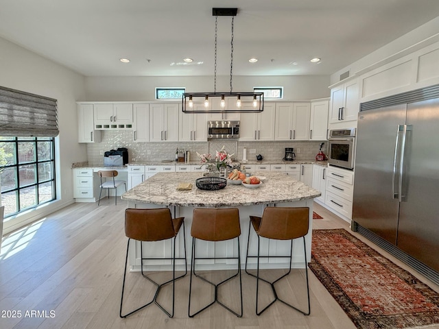 kitchen with a kitchen bar, white cabinets, a center island, and stainless steel appliances