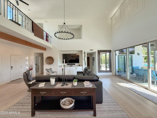 living room with a high ceiling, baseboards, visible vents, and light wood finished floors