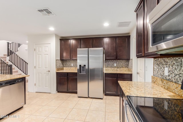 kitchen featuring stainless steel appliances, dark brown cabinetry, backsplash, light stone counters, and recessed lighting