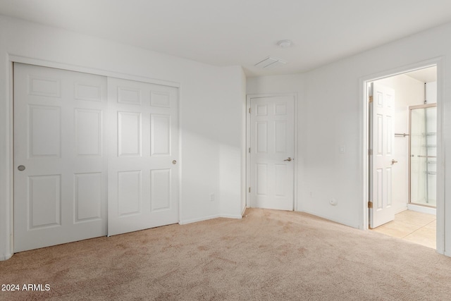unfurnished bedroom with carpet flooring, ensuite bathroom, and a closet