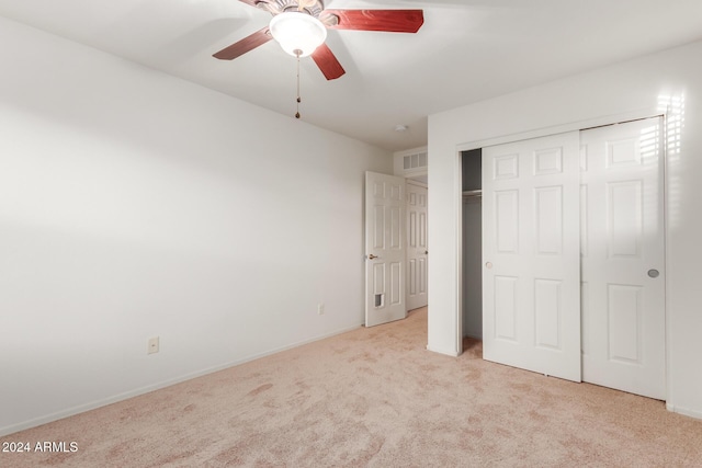 unfurnished bedroom featuring light carpet, a closet, baseboards, and a ceiling fan