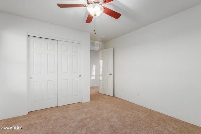 unfurnished bedroom with carpet flooring, a closet, and a ceiling fan