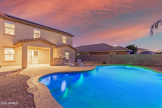 pool at dusk with a patio area