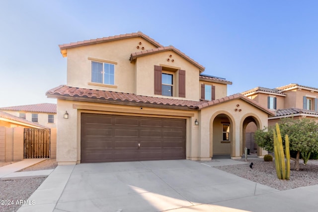 mediterranean / spanish-style home with a garage, driveway, and stucco siding