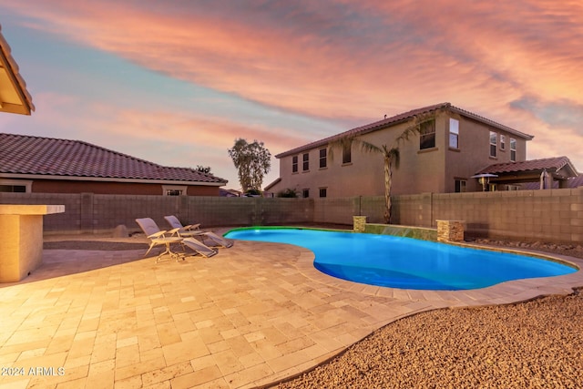 pool at dusk featuring a patio area and a fenced backyard