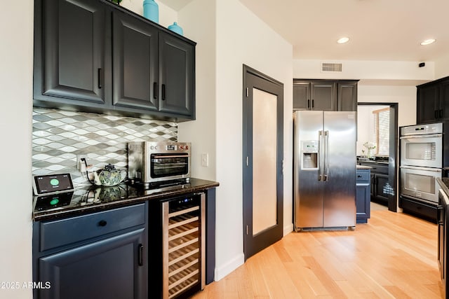 kitchen featuring stainless steel appliances, decorative backsplash, wine cooler, and light hardwood / wood-style flooring