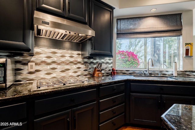 kitchen featuring tasteful backsplash, sink, extractor fan, and dark stone countertops