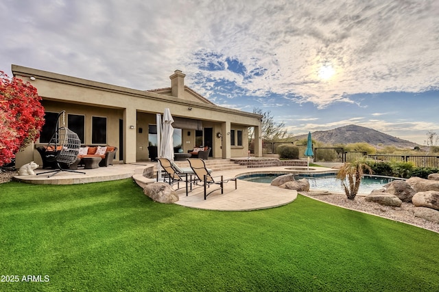 rear view of property with a mountain view, a swimming pool with hot tub, a patio, and a yard