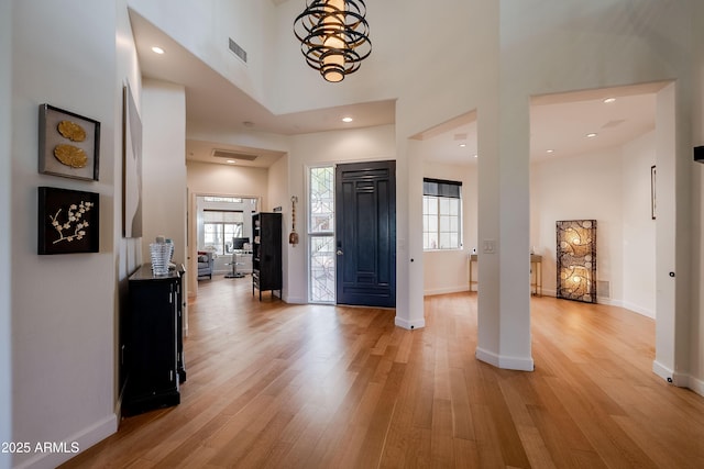 entryway with an inviting chandelier, a high ceiling, and light hardwood / wood-style flooring