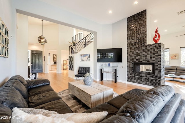 living room featuring a high ceiling, a multi sided fireplace, and light hardwood / wood-style flooring