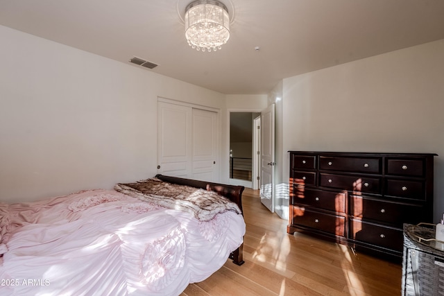 bedroom with a closet, light hardwood / wood-style floors, and an inviting chandelier