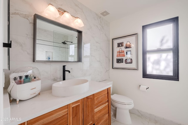 bathroom featuring toilet, vanity, tile walls, and tasteful backsplash