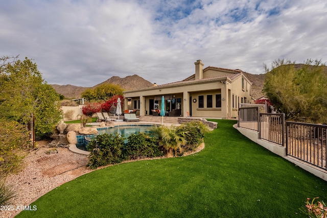 rear view of property featuring a lawn, a patio area, a mountain view, and a fenced in pool