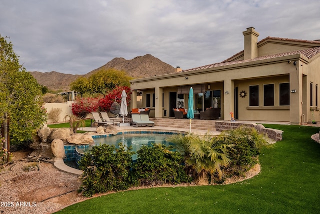 back of property featuring a fenced in pool, a patio area, a mountain view, and a yard