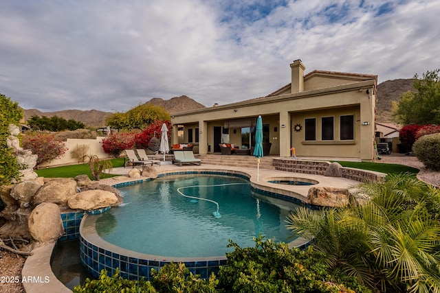 view of swimming pool featuring an in ground hot tub, a patio area, and a mountain view