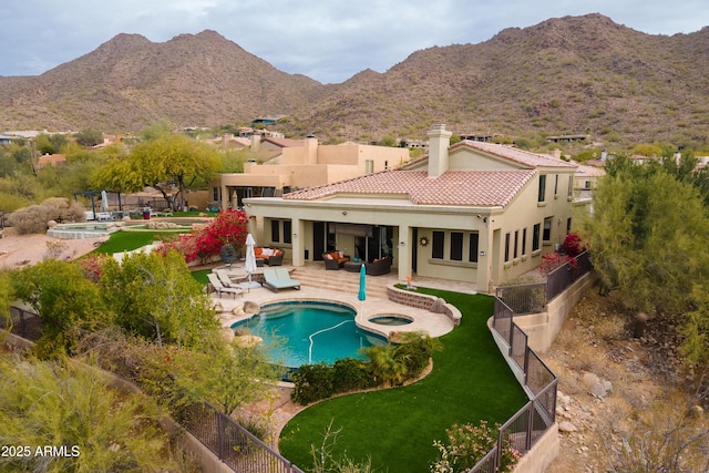 rear view of house with a swimming pool with hot tub, a patio area, and a mountain view