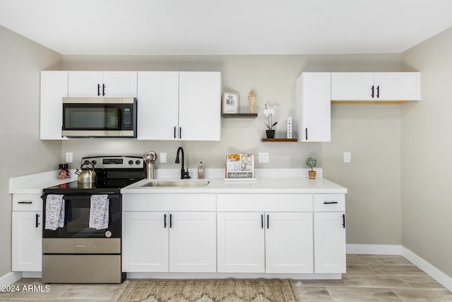 kitchen featuring stainless steel appliances, white cabinets, sink, and light wood-type flooring