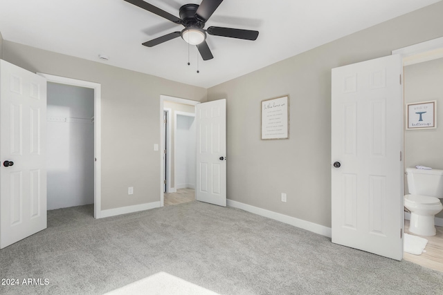 unfurnished bedroom with a closet, light colored carpet, ceiling fan, and ensuite bath