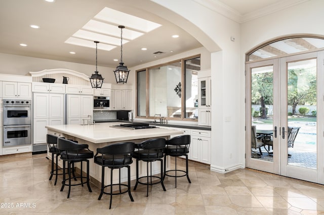 kitchen with white cabinetry, french doors, a center island, and decorative light fixtures