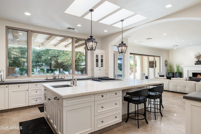 kitchen featuring a center island with sink, decorative light fixtures, white cabinetry, and sink