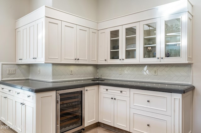 bar with decorative backsplash, white cabinets, and beverage cooler