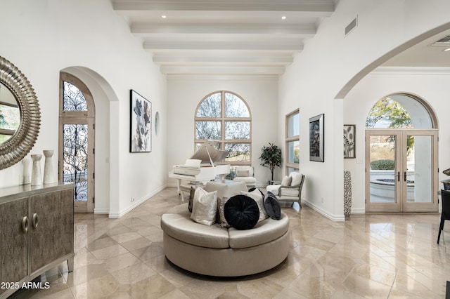 sitting room with beam ceiling, a wealth of natural light, and french doors