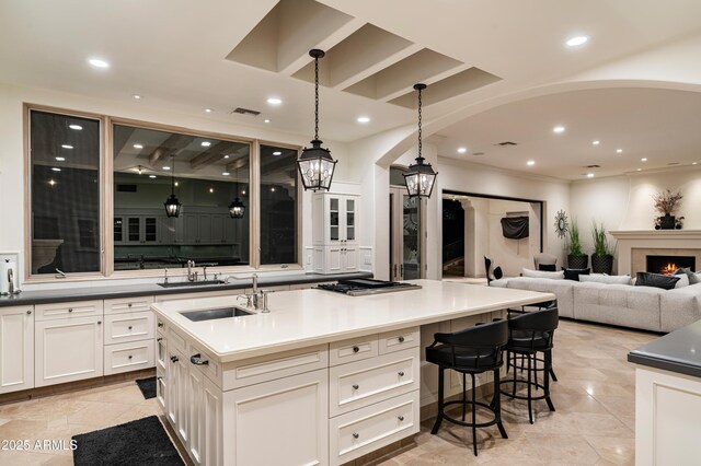 kitchen with pendant lighting, sink, white cabinetry, and a kitchen island with sink