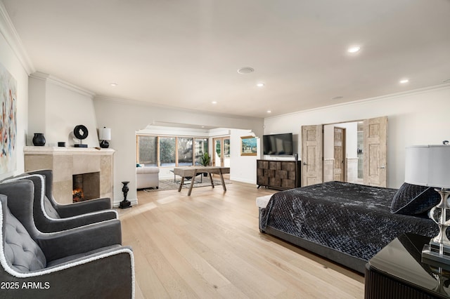 bedroom featuring light hardwood / wood-style floors, crown molding, and a high end fireplace