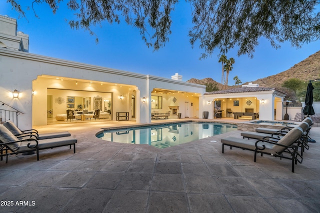 pool at dusk with outdoor lounge area, a mountain view, and a patio