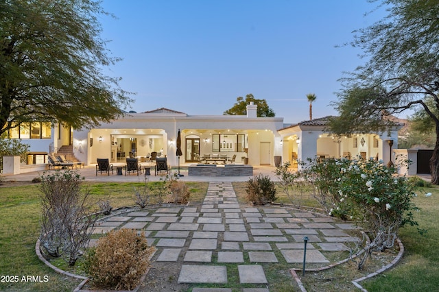 back house at dusk featuring outdoor lounge area and a patio