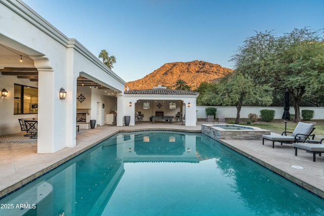 view of swimming pool with a mountain view, a patio area, an in ground hot tub, and exterior fireplace