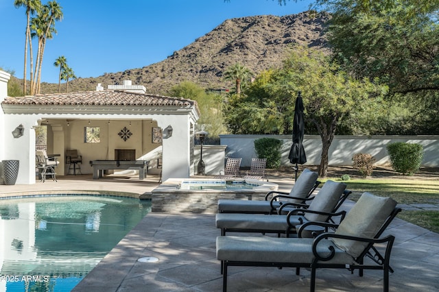 view of swimming pool with a mountain view, a patio area, and an in ground hot tub