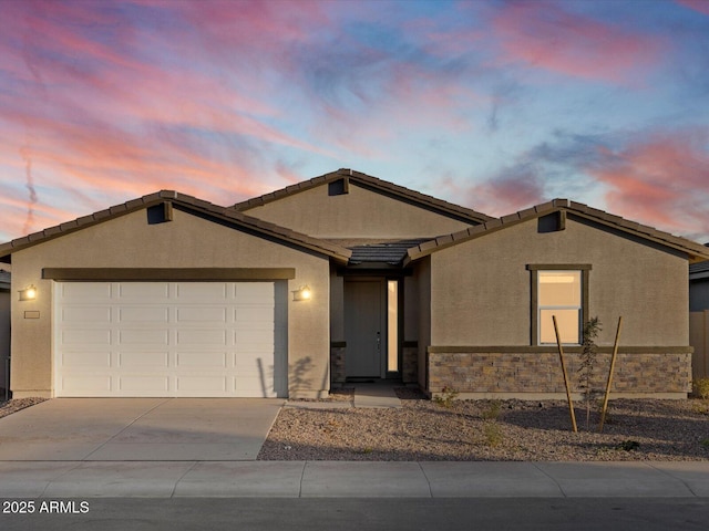 ranch-style home featuring a garage, concrete driveway, stone siding, and stucco siding