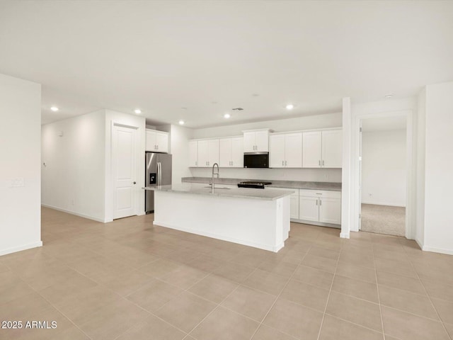 kitchen featuring light countertops, a kitchen island with sink, a sink, white cabinetry, and stainless steel fridge with ice dispenser