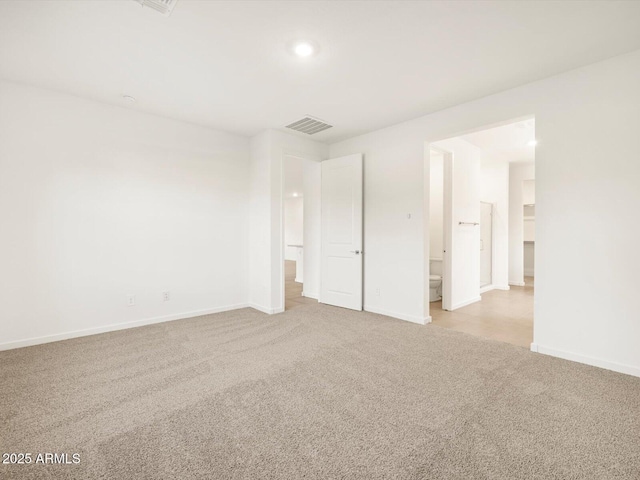 unfurnished bedroom with light colored carpet, ensuite bath, visible vents, and baseboards