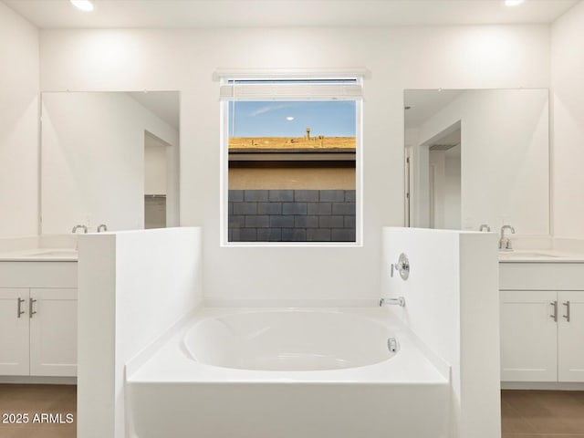 bathroom with two vanities, a sink, a bath, and recessed lighting