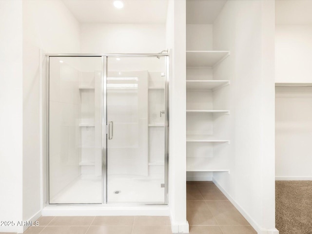 bathroom with baseboards, a stall shower, a closet, and tile patterned floors