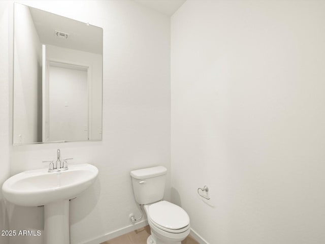 half bath featuring tile patterned flooring, baseboards, visible vents, and toilet