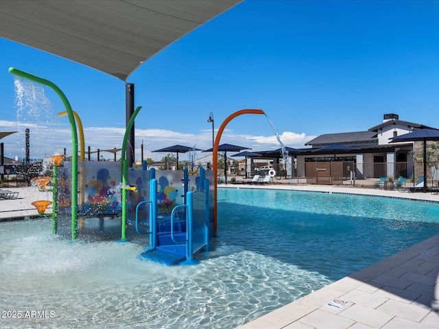 community pool featuring playground community, a water play area, and fence