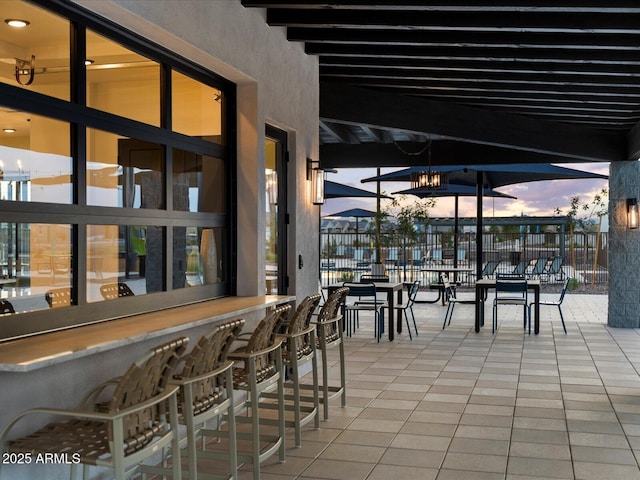 patio terrace at dusk with fence and outdoor dry bar