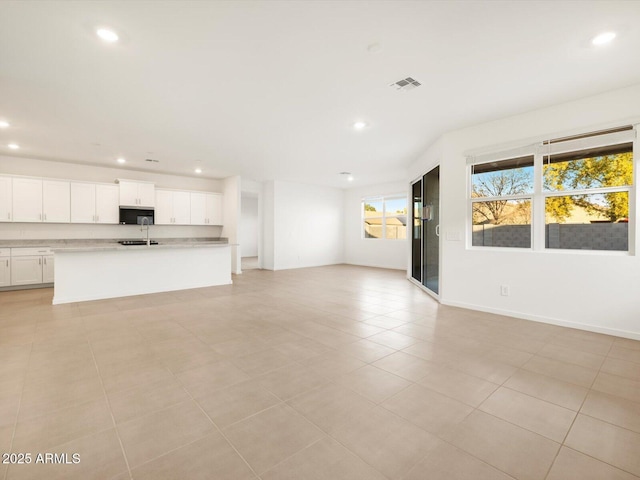 unfurnished living room with recessed lighting, visible vents, a sink, and baseboards