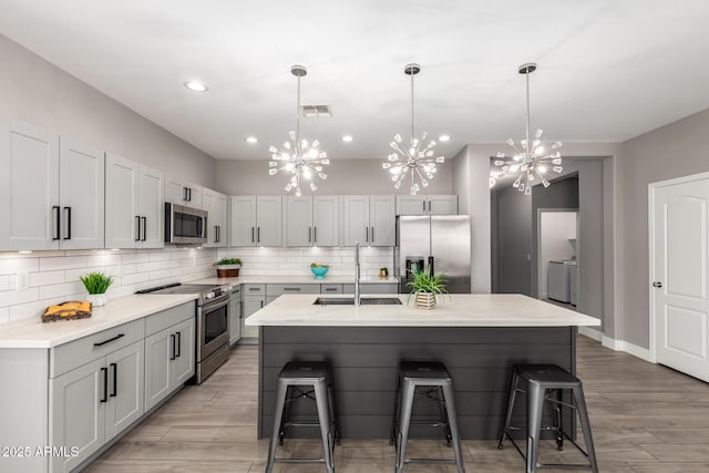 kitchen with backsplash, a chandelier, a kitchen bar, stainless steel appliances, and a sink