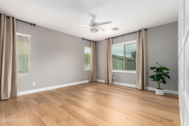 empty room featuring visible vents, baseboards, light wood-type flooring, and ceiling fan