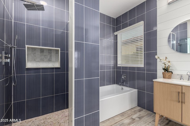 bathroom with a bath, wood finished floors, vanity, and a walk in shower